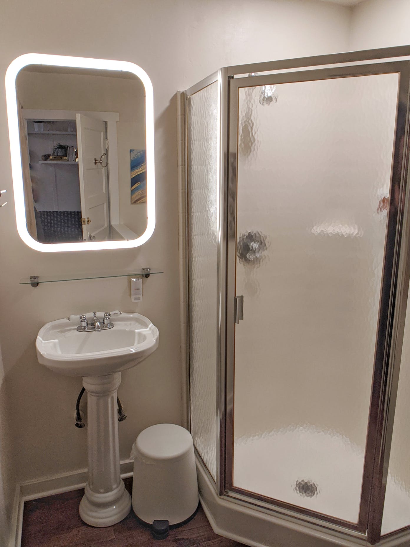 A bathroom with a sink , shower and mirror.