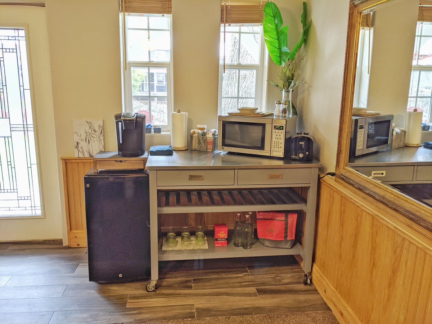 A kitchen with a microwave , refrigerator , and a mirror.