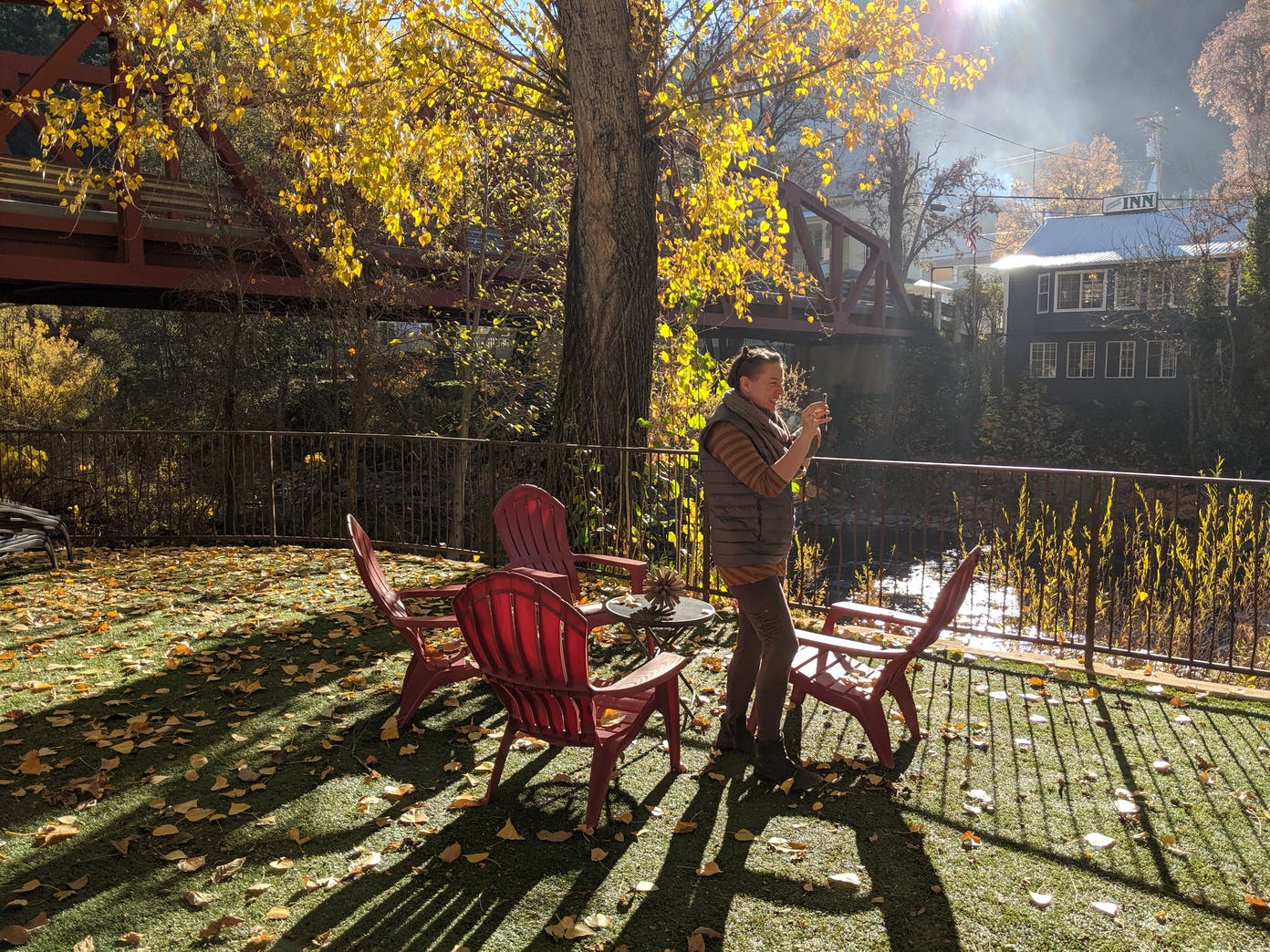 A man is standing next to a table and chairs in a park.