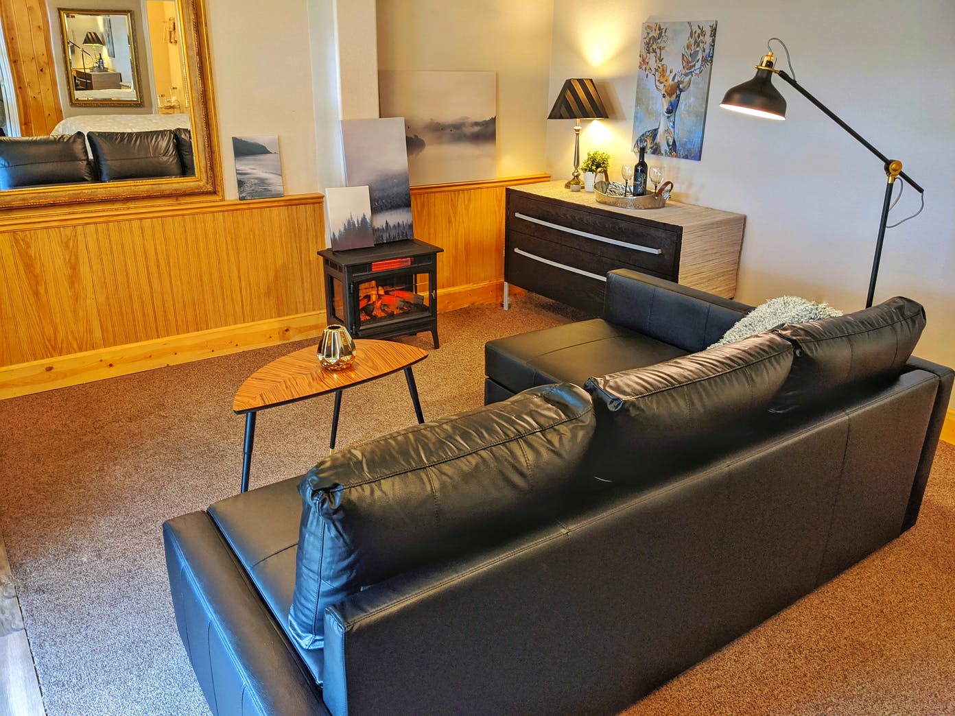 A living room with a couch , table , lamp and mirror.