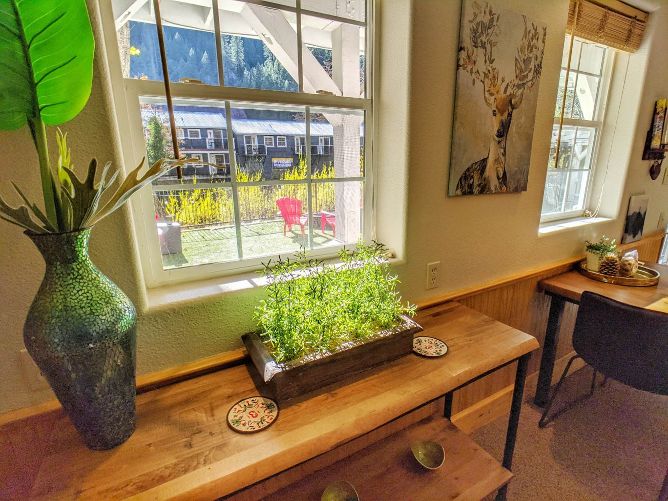 A wooden table with a potted plant on it in front of a window.