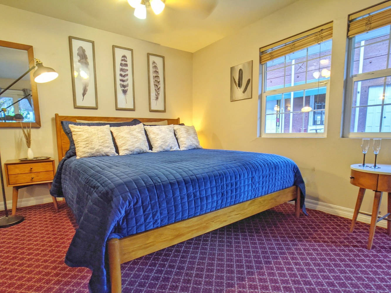 A bedroom with a bed , nightstand , mirror and window.