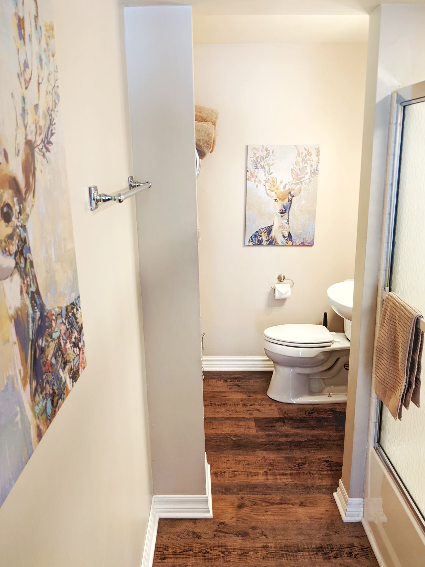 A bathroom with a toilet , sink , and painting on the wall.