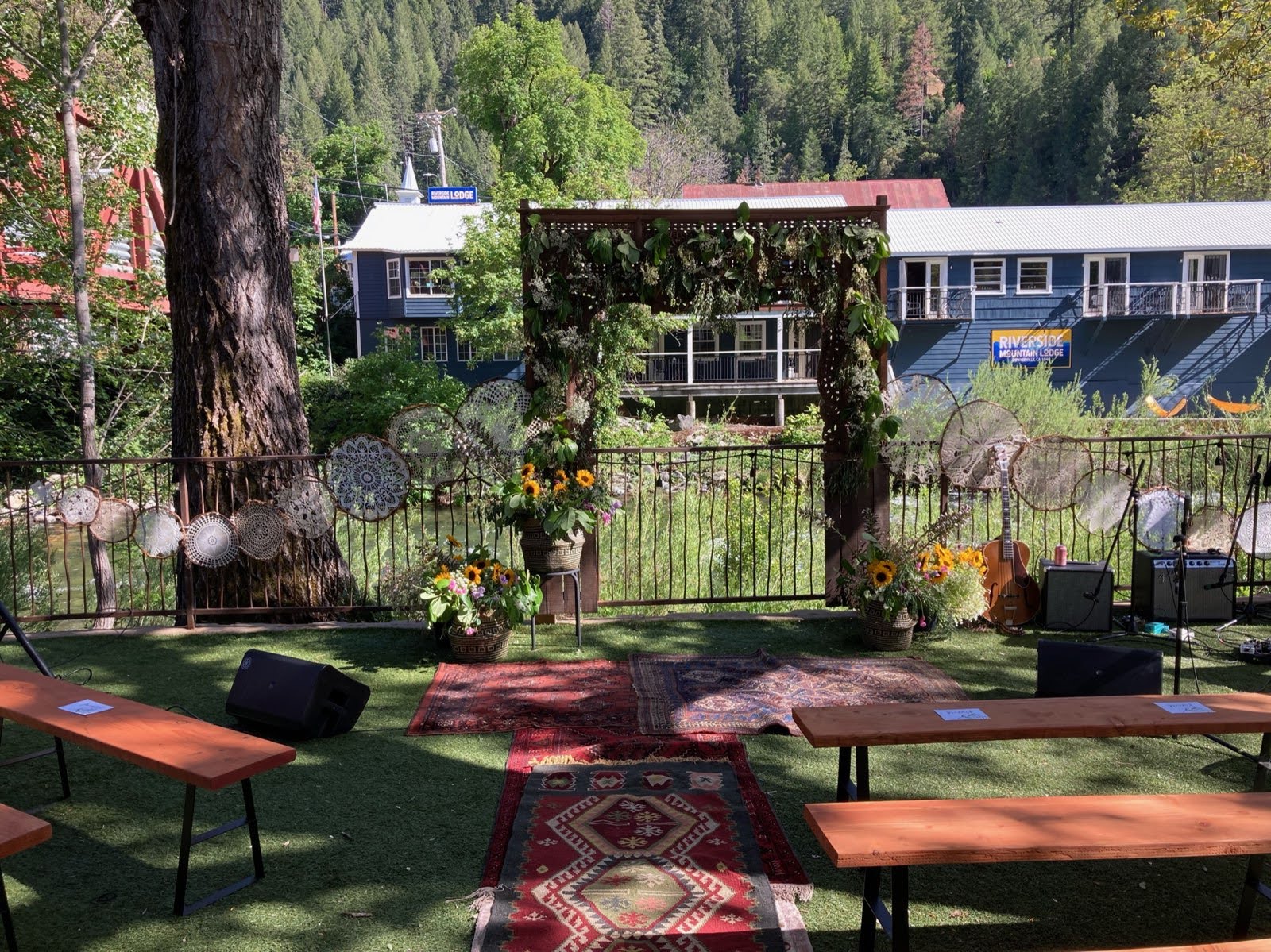 A wedding ceremony is taking place in a park with tables and benches.