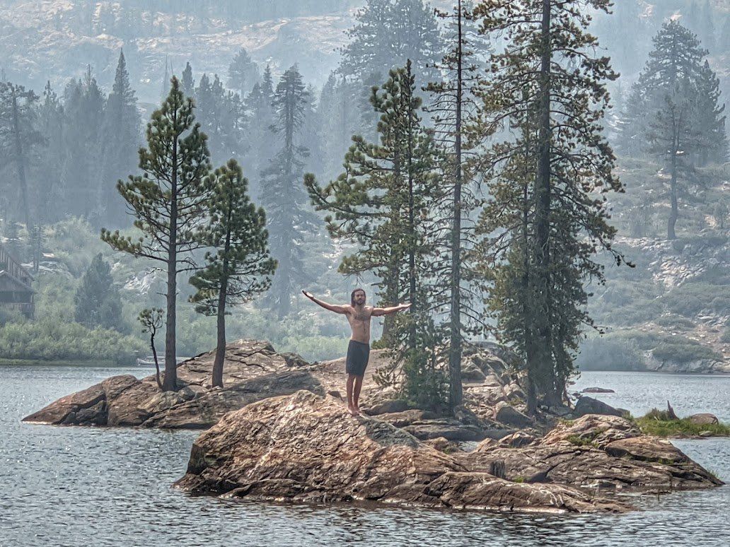 A man is standing on a small island in the middle of a lake.