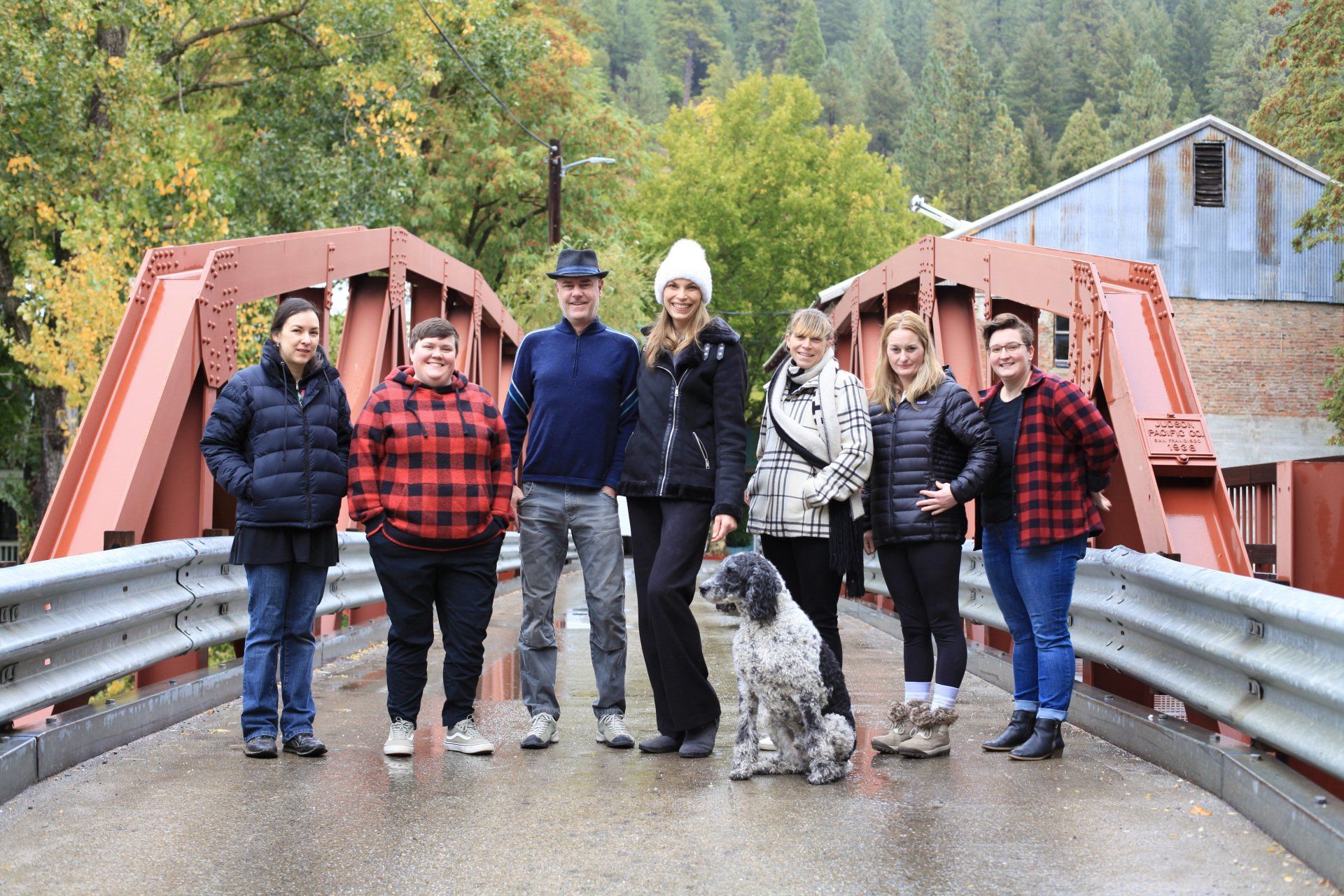 A group of people standing on a bridge with a dog.