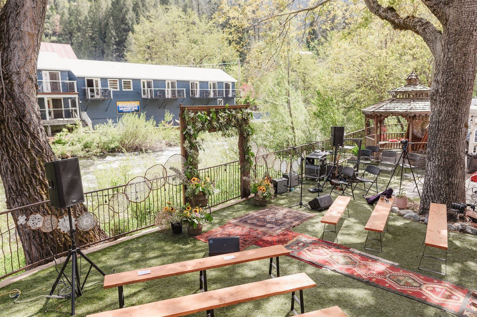 A wedding ceremony is taking place under a tree in the woods.