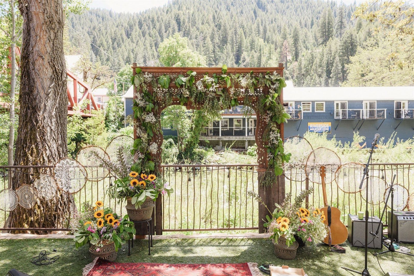 A wooden arch decorated with flowers and leaves is sitting in the middle of a grassy field.