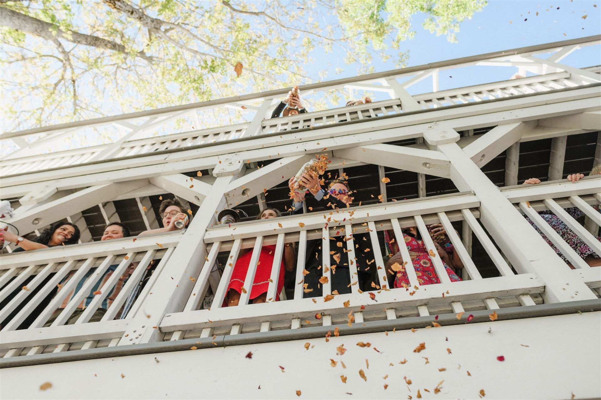 A group of people are standing on a balcony throwing confetti.