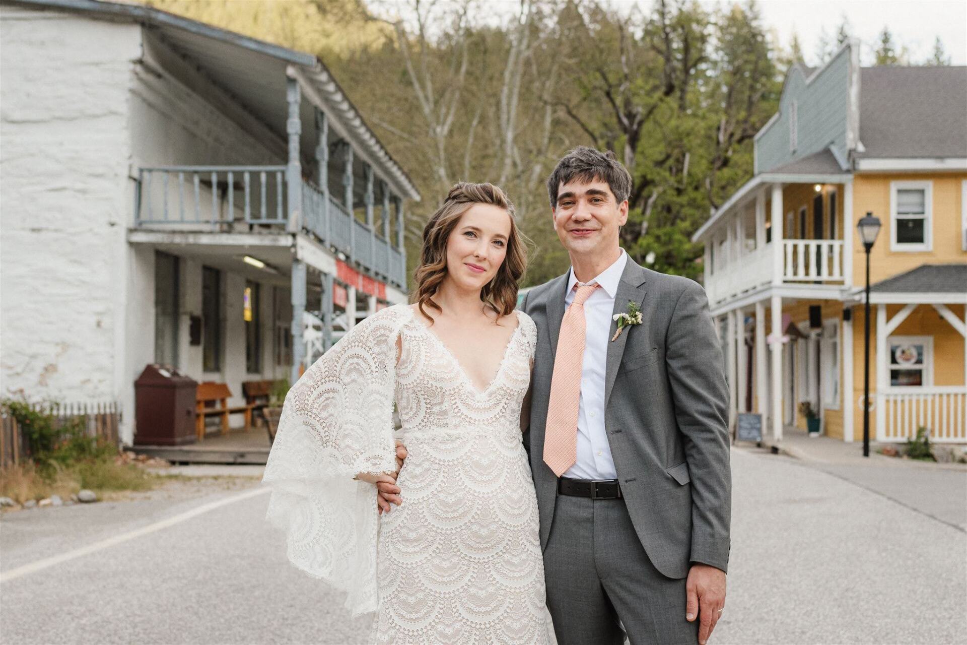 A bride and groom are posing for a picture in front of a small town.