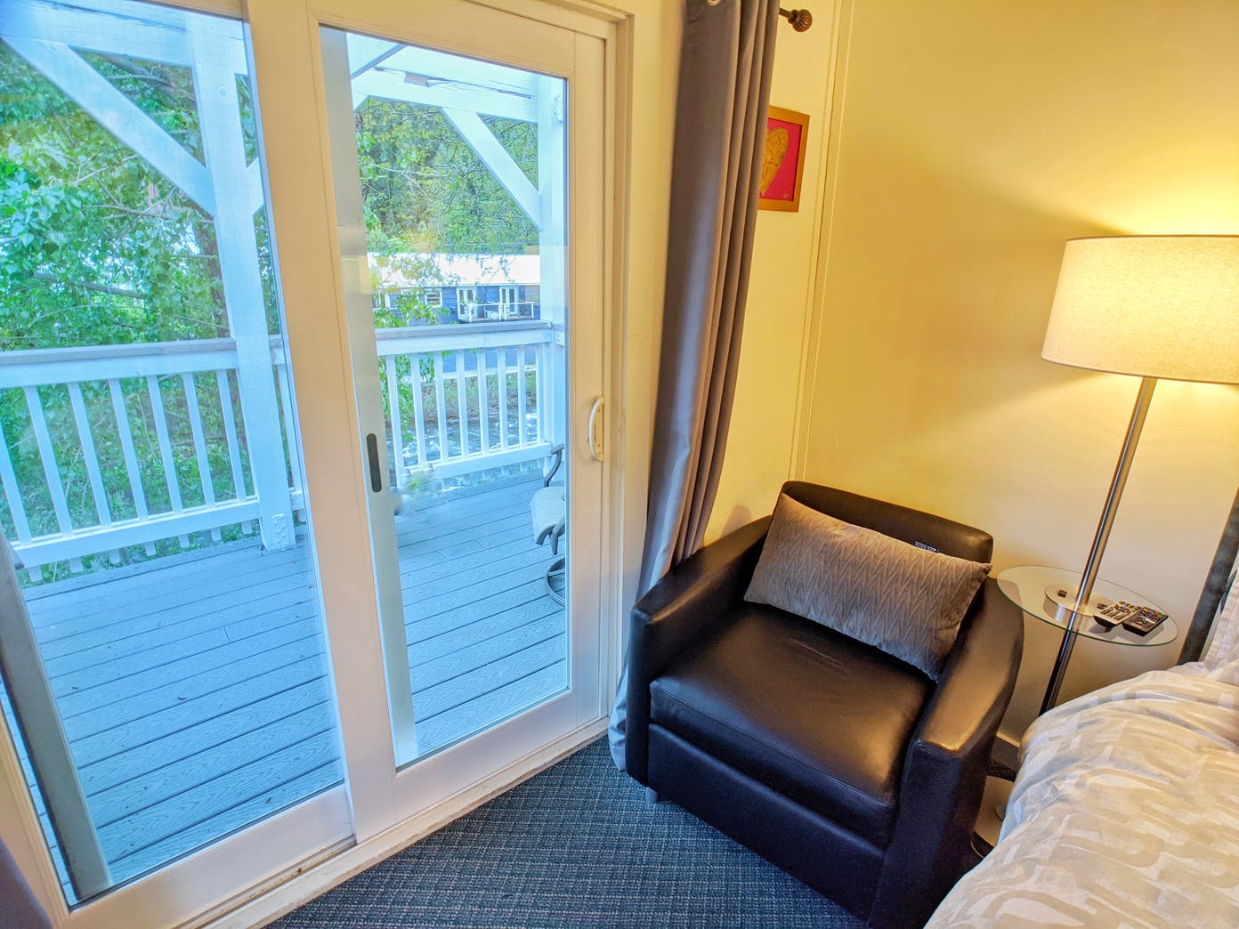 A hotel room with a chair and a sliding glass door leading to a deck.
