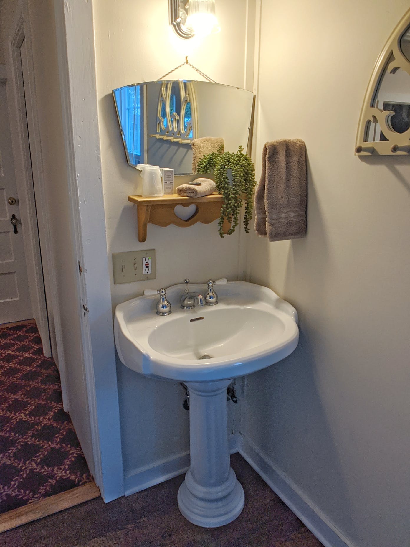 A bathroom with a pedestal sink and a mirror.