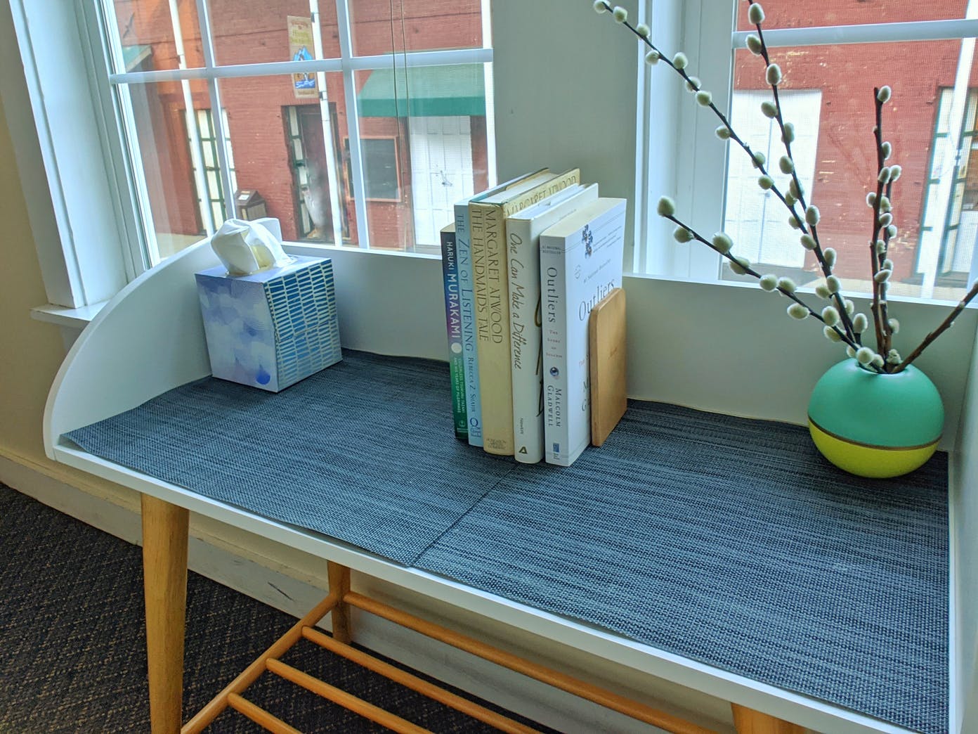 A stack of books sitting on top of a table next to a window.