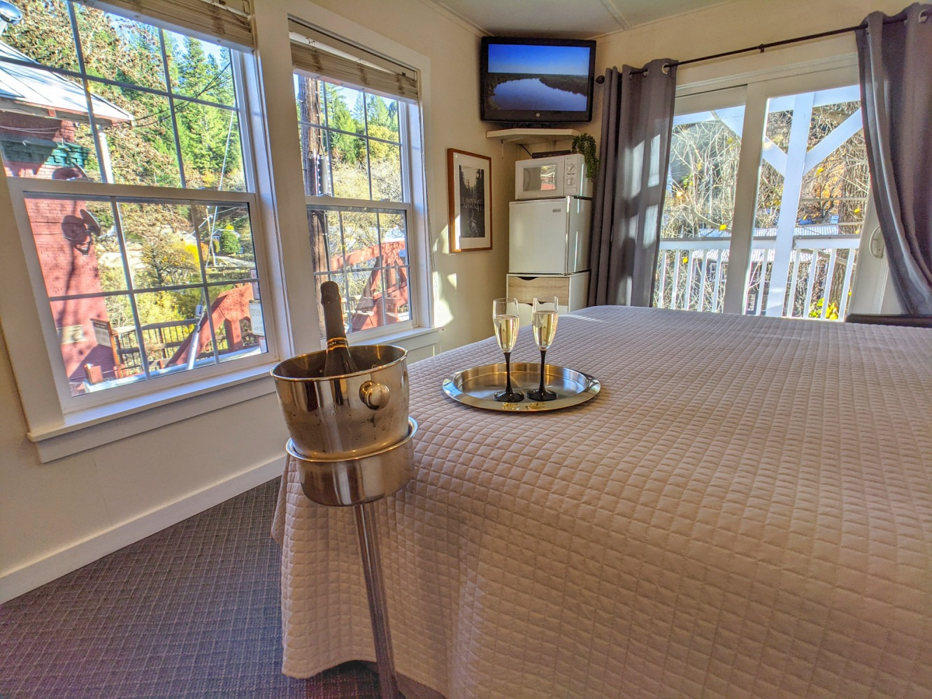 There is a bucket of champagne and two glasses on the bed.