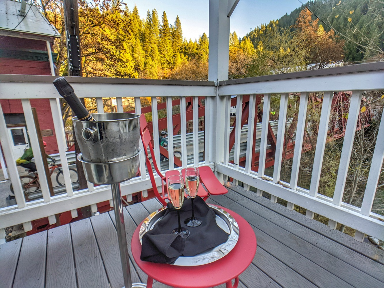 A balcony with a bucket of champagne and two glasses on it.