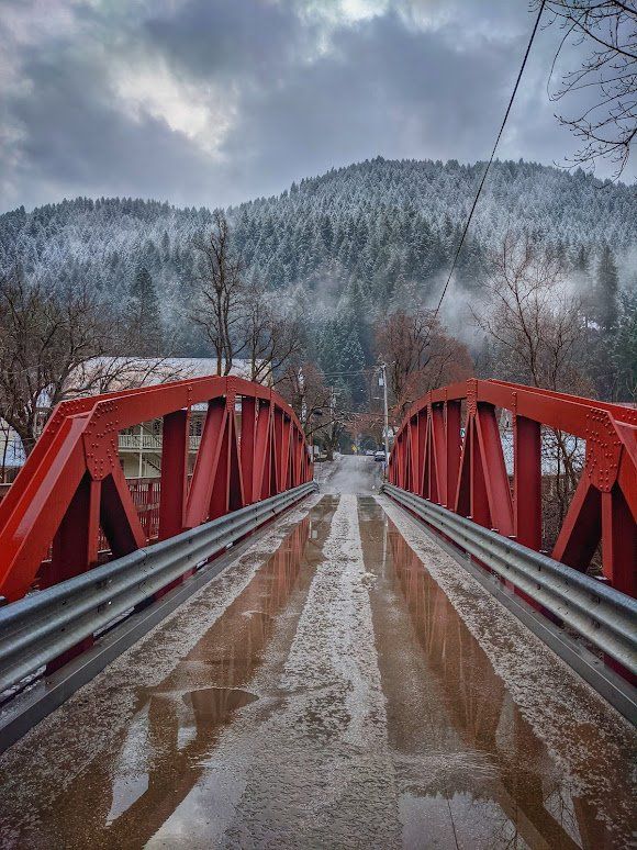 A red bridge over a river with mountains in the background.