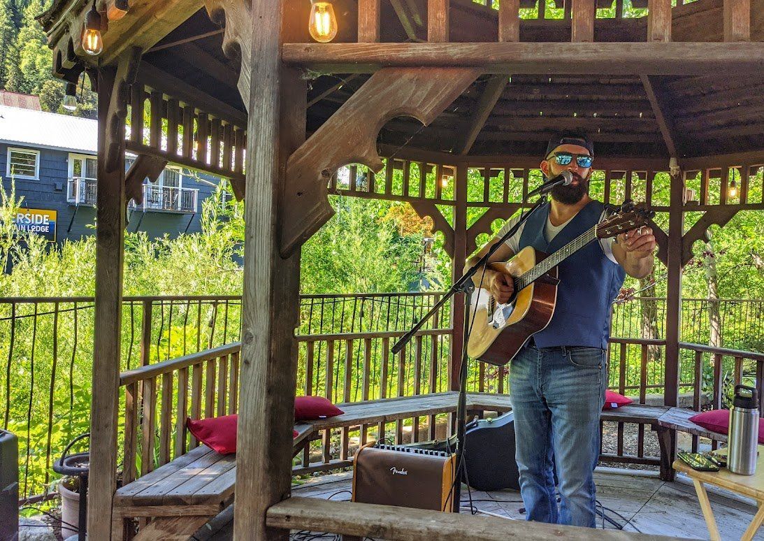 A man is playing a guitar in a gazebo.