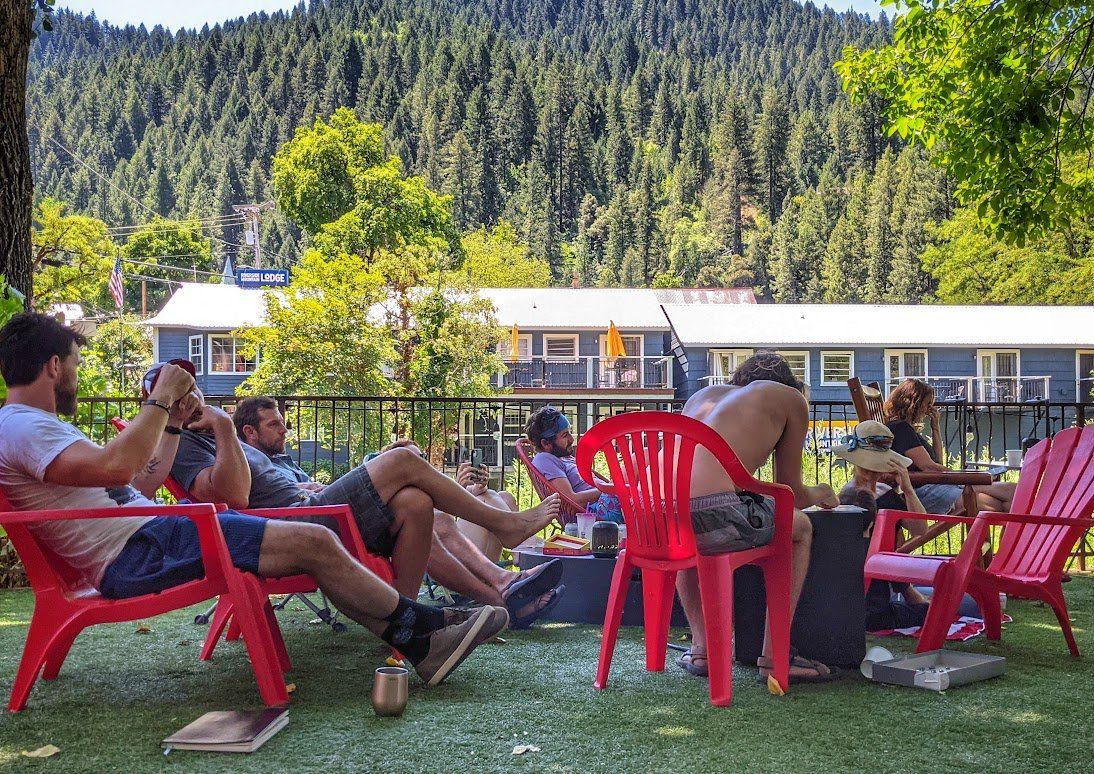 A group of people are sitting in red chairs in a park.