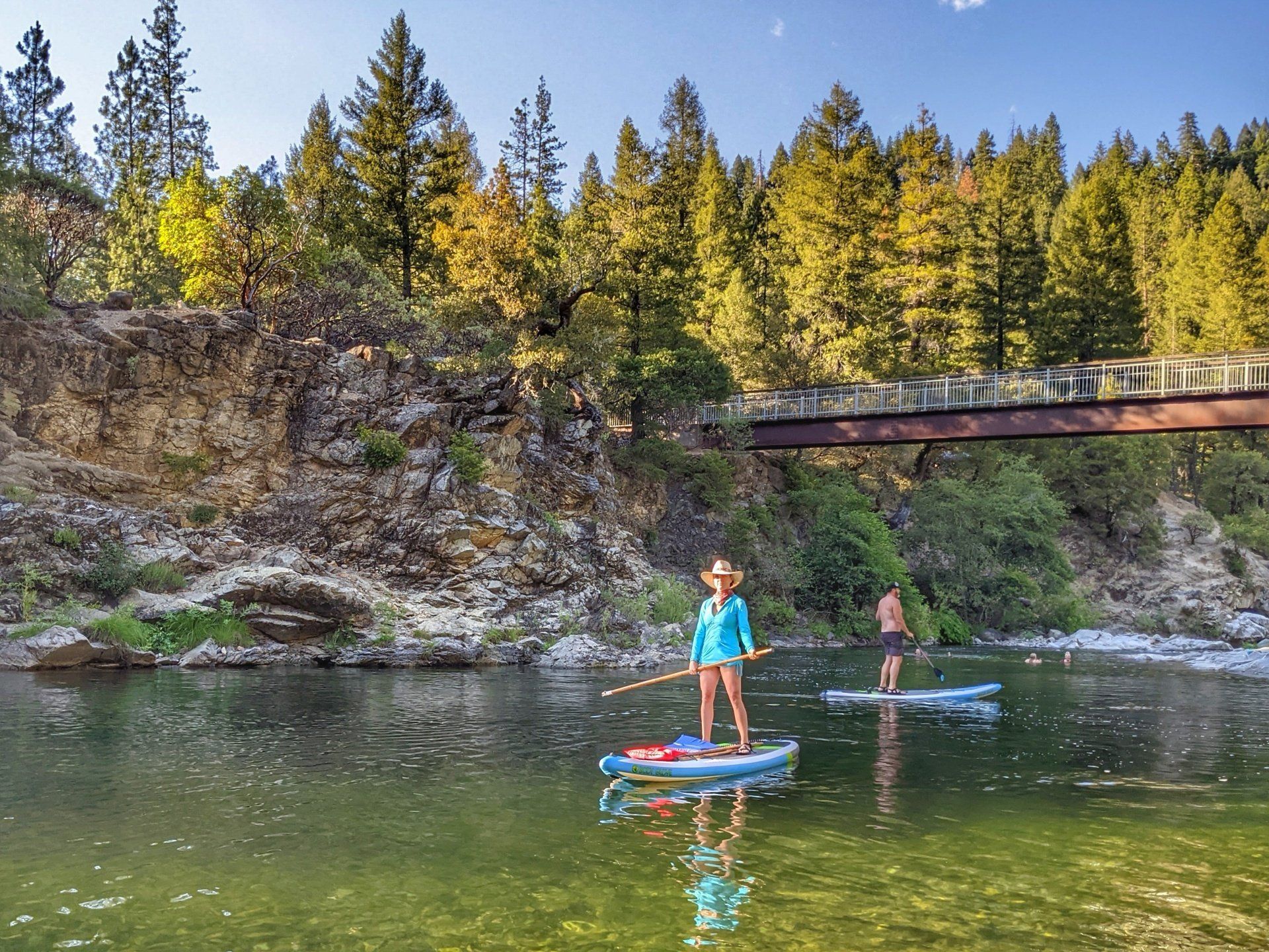 A woman is standing on a paddle board in a river.