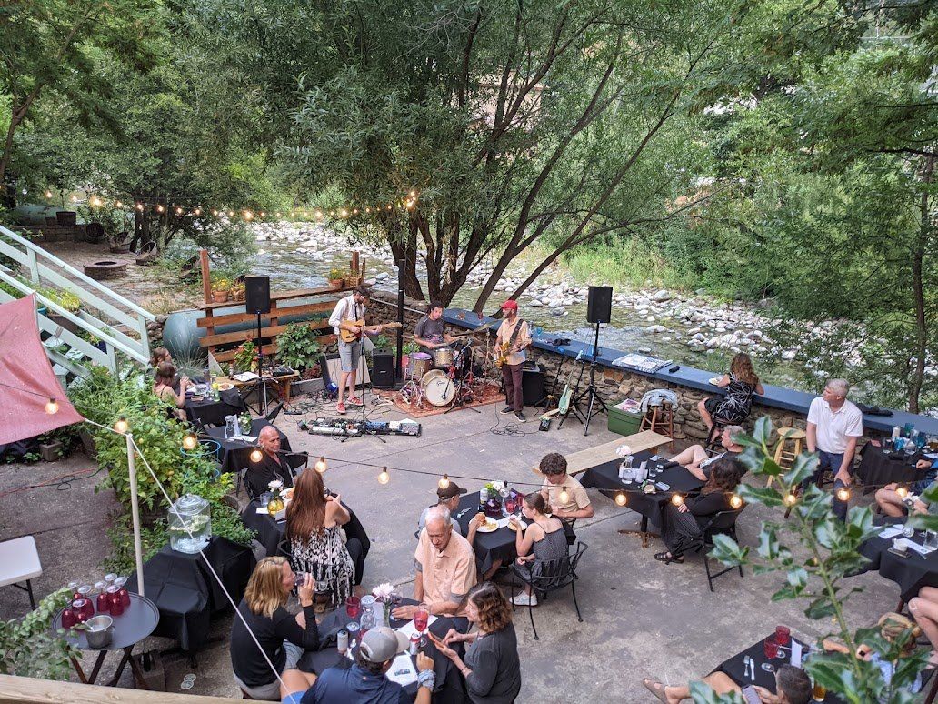 A group of people are sitting at tables watching a band play.