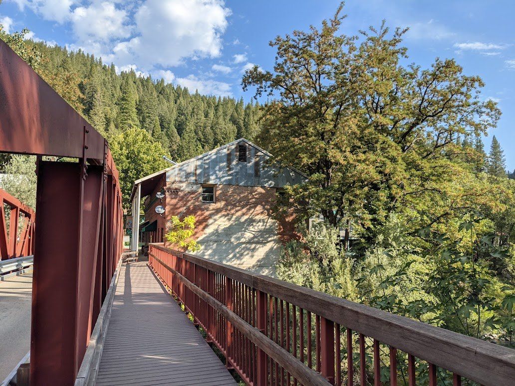 A bridge over a river surrounded by trees on a sunny day.