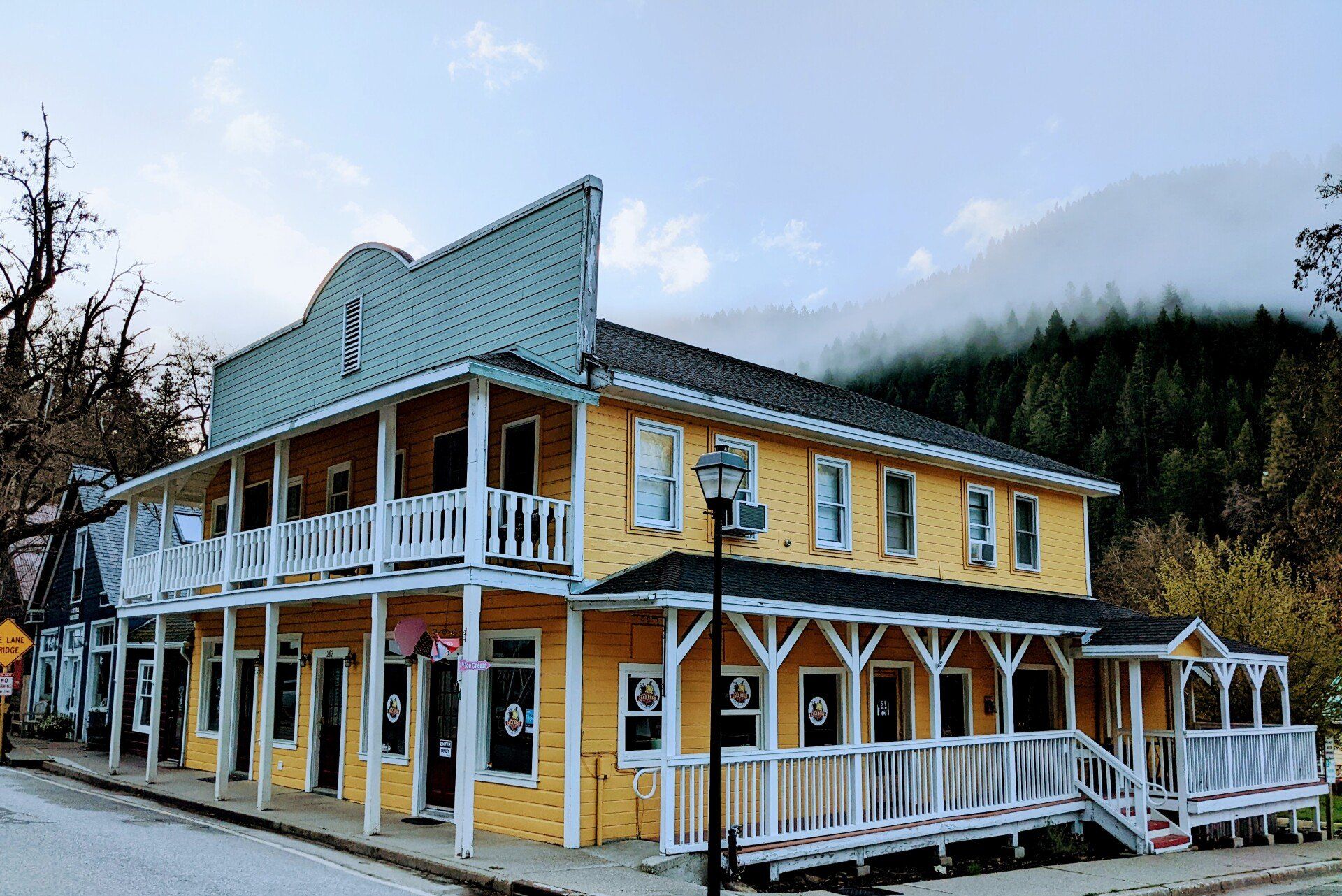 A large yellow building with a green roof and white porches