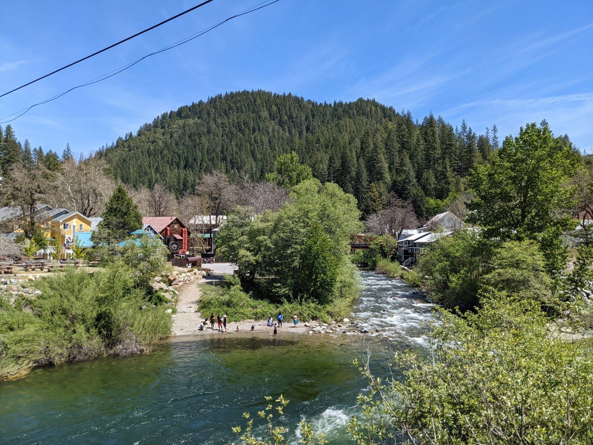 A river runs through a small town surrounded by trees and houses.