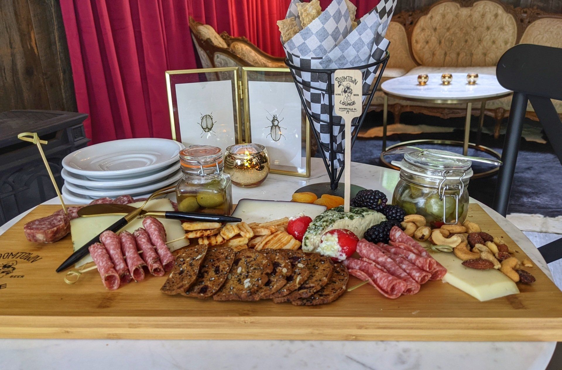 A wooden cutting board filled with meat , cheese , crackers and nuts.