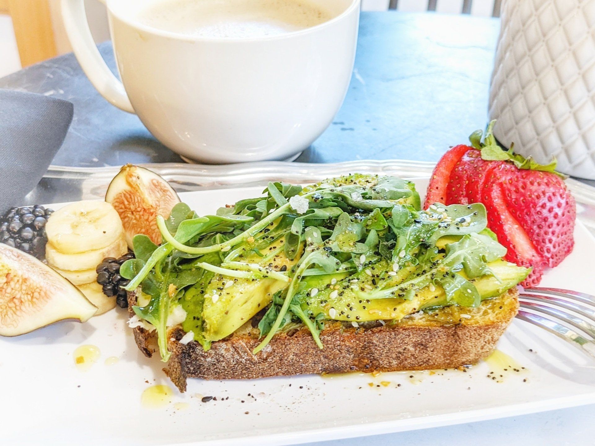 A close up of a plate of food with a cup of coffee in the background.