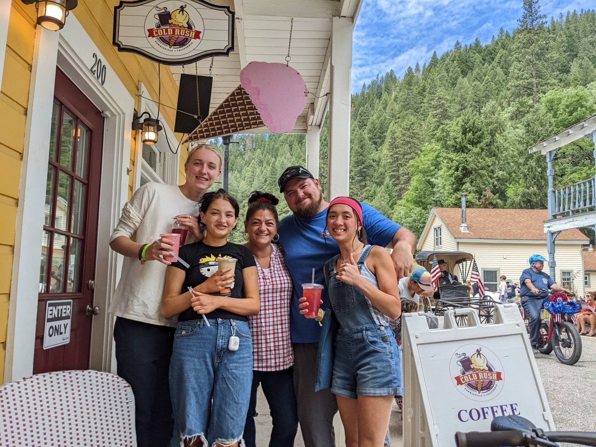 A group of people are posing for a picture in front of a coffee shop.