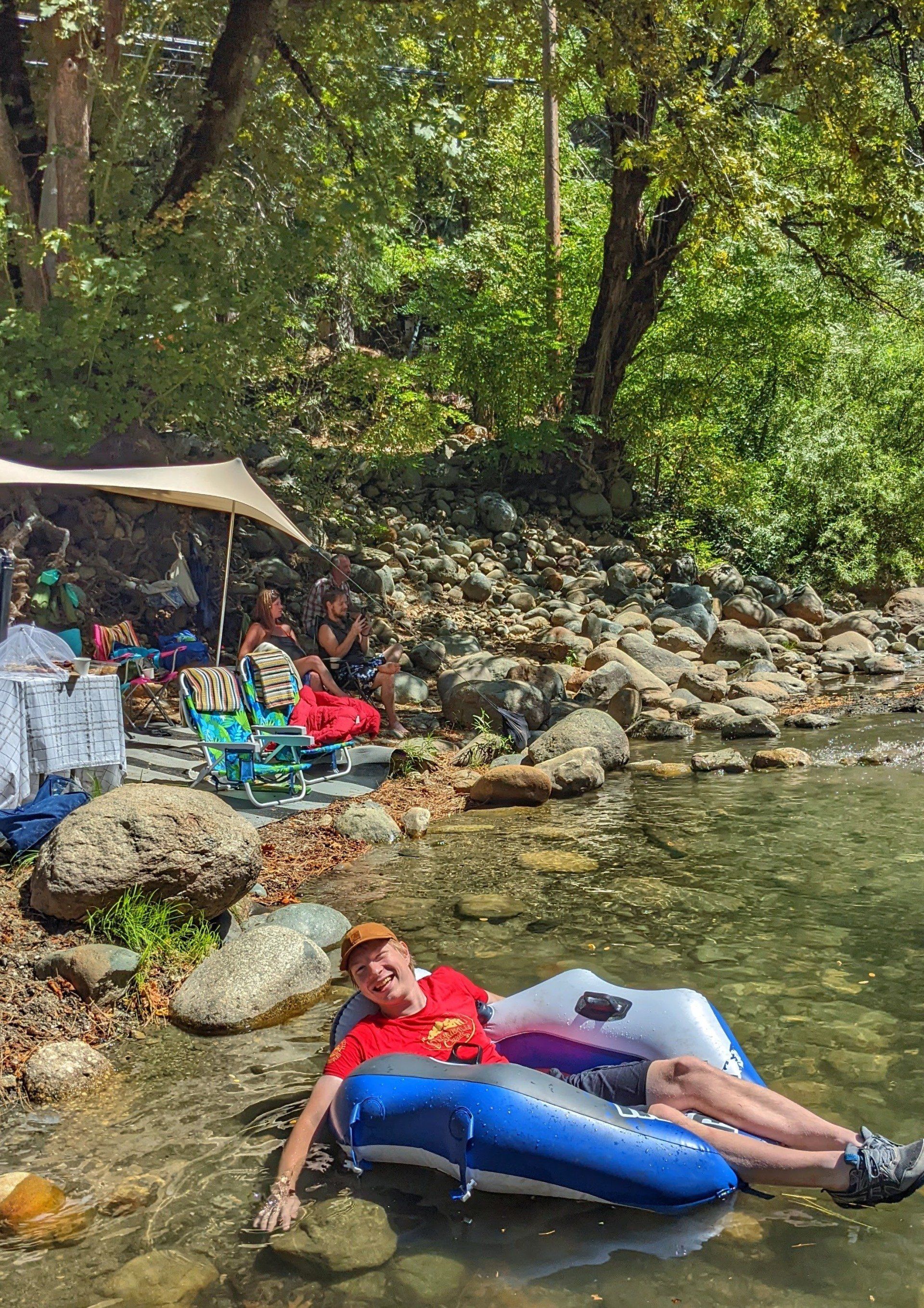 A man is laying on a tube in a river.