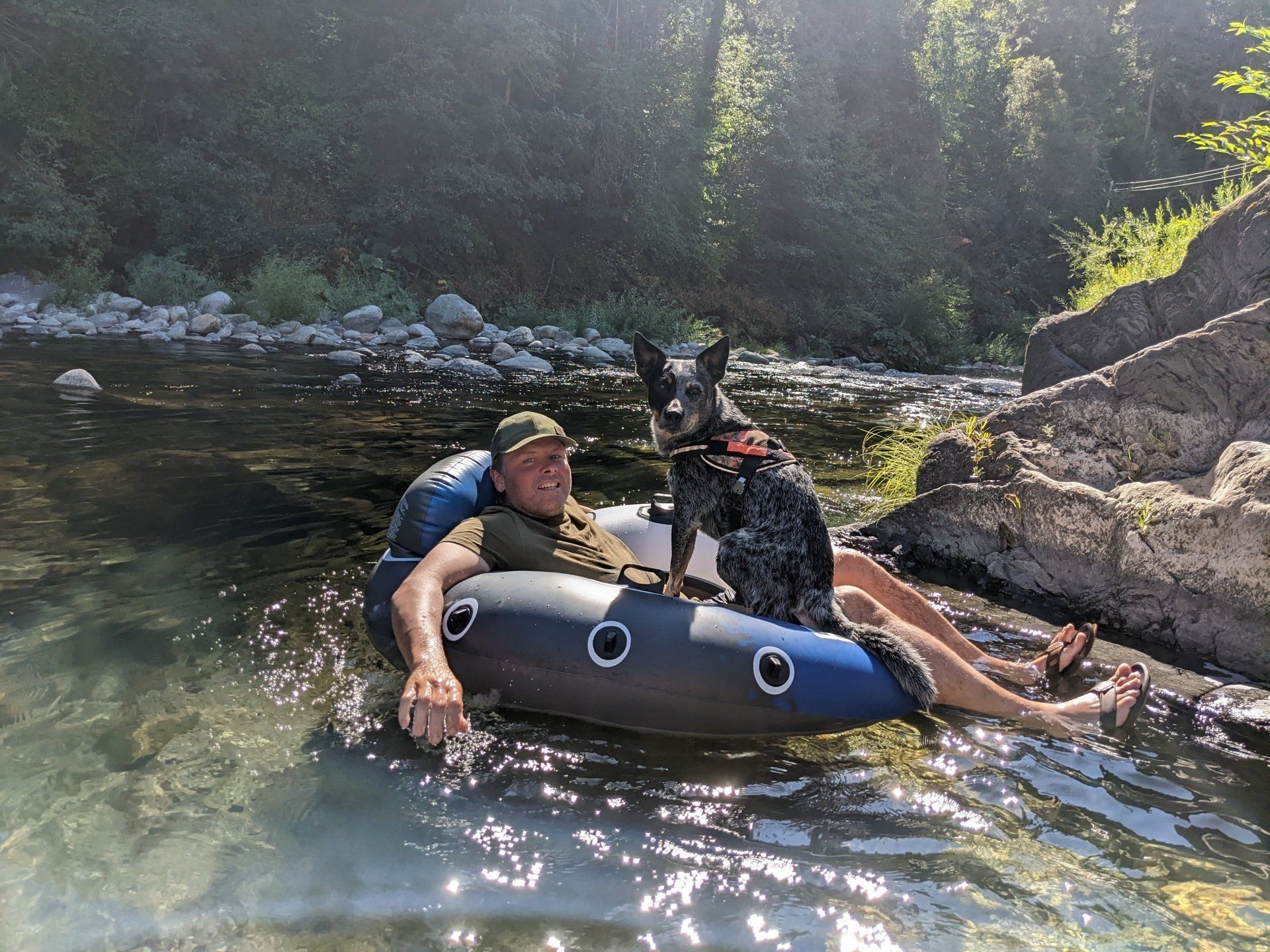 A man and a dog are floating down a river in a tube.