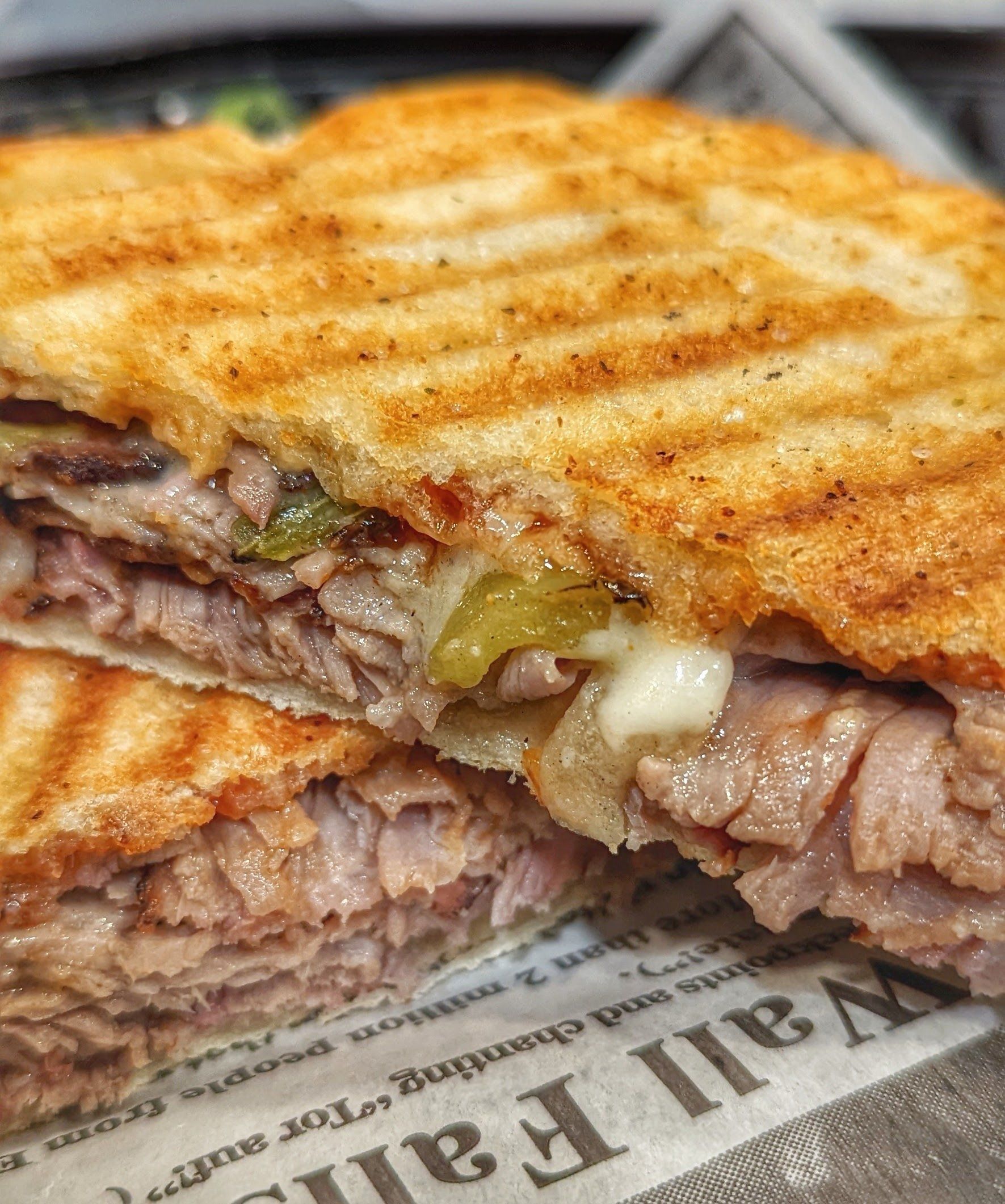 A close up of a sandwich on a newspaper on a table.