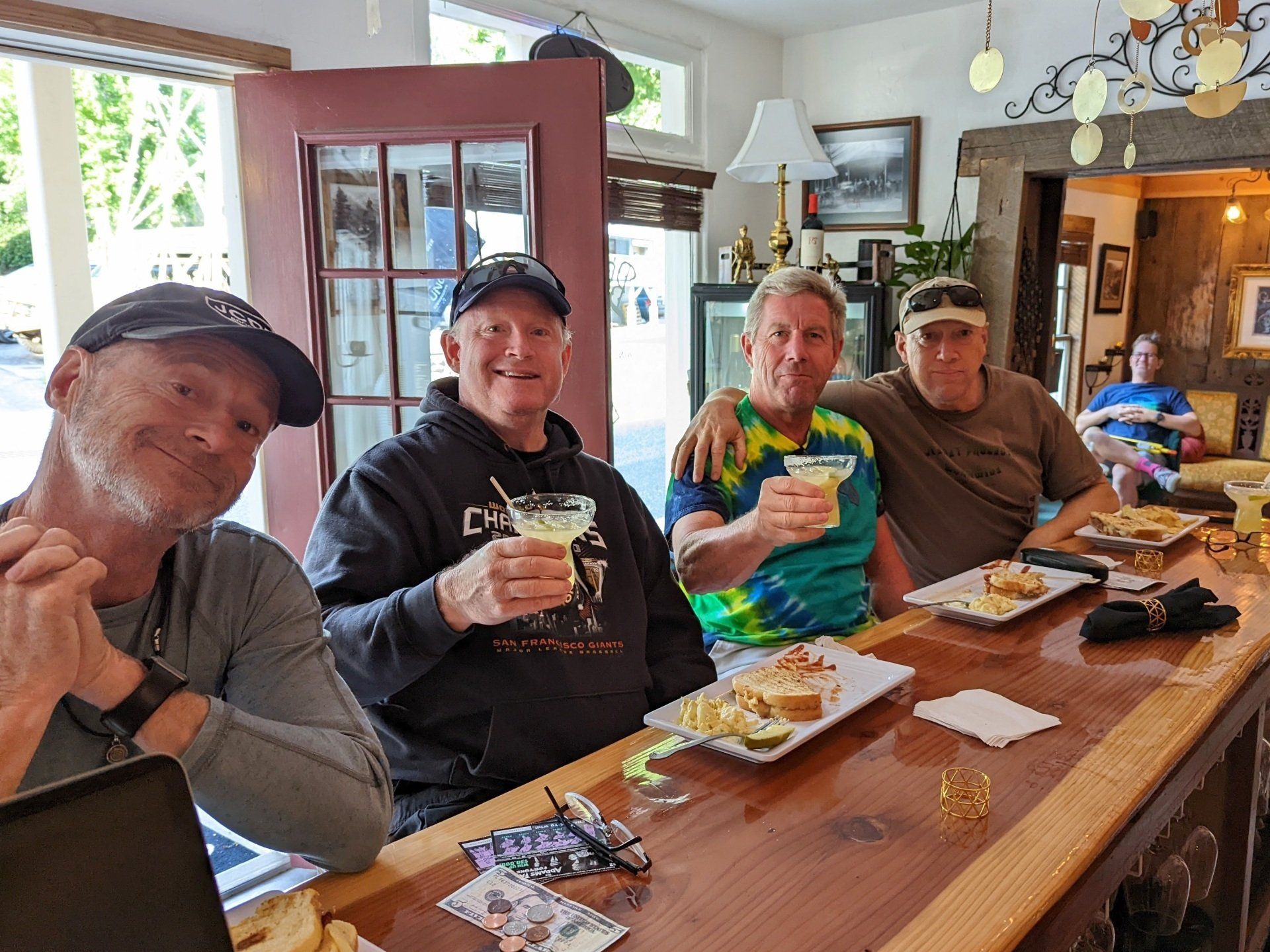 A group of men are sitting at a bar holding drinks.