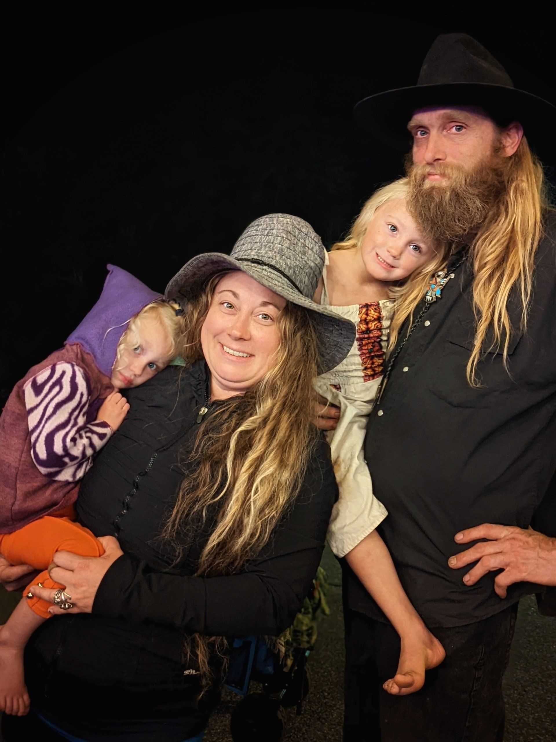 A man with a beard is standing next to a woman and two children.