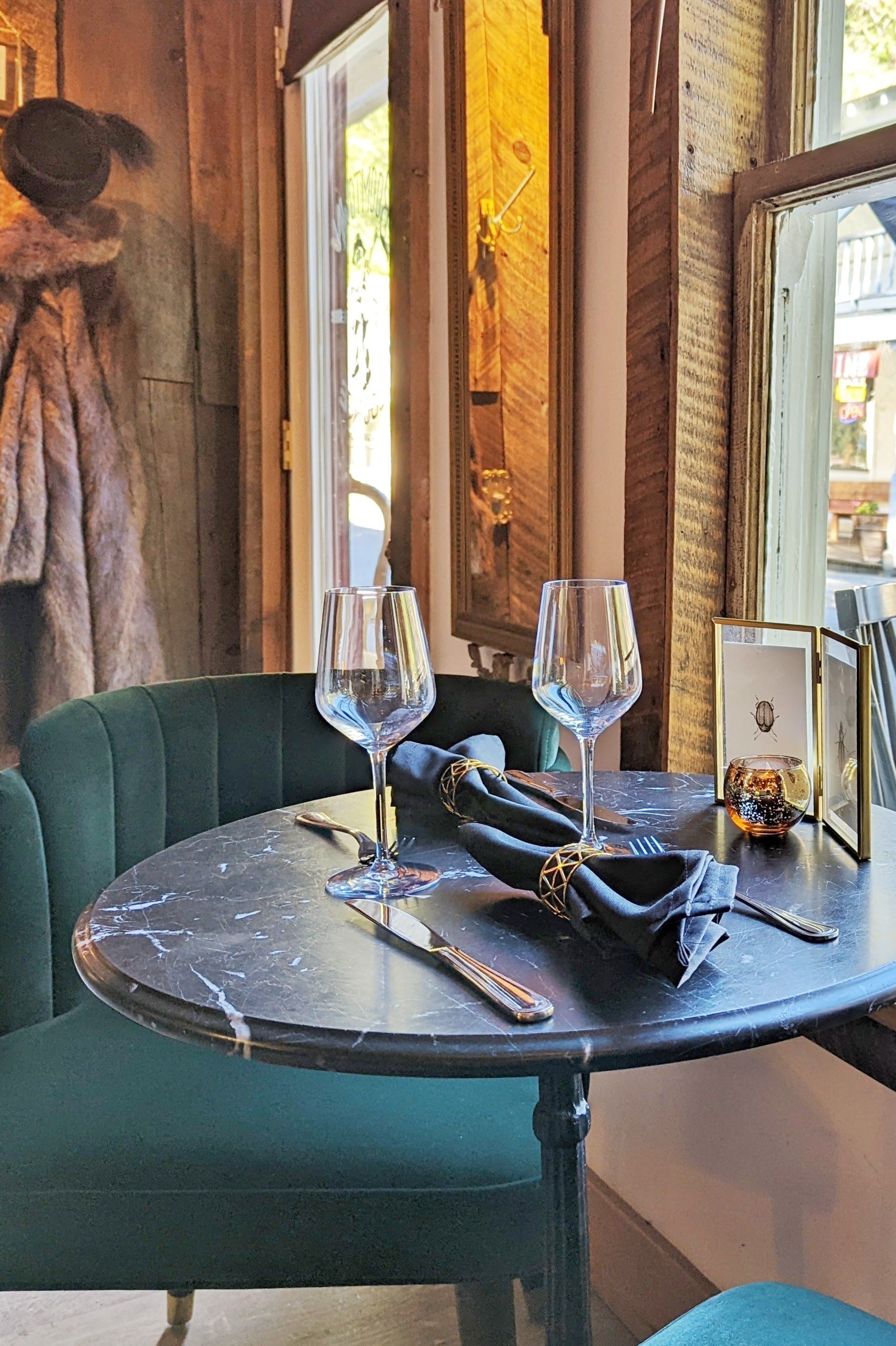 A table with two wine glasses on it in a restaurant.