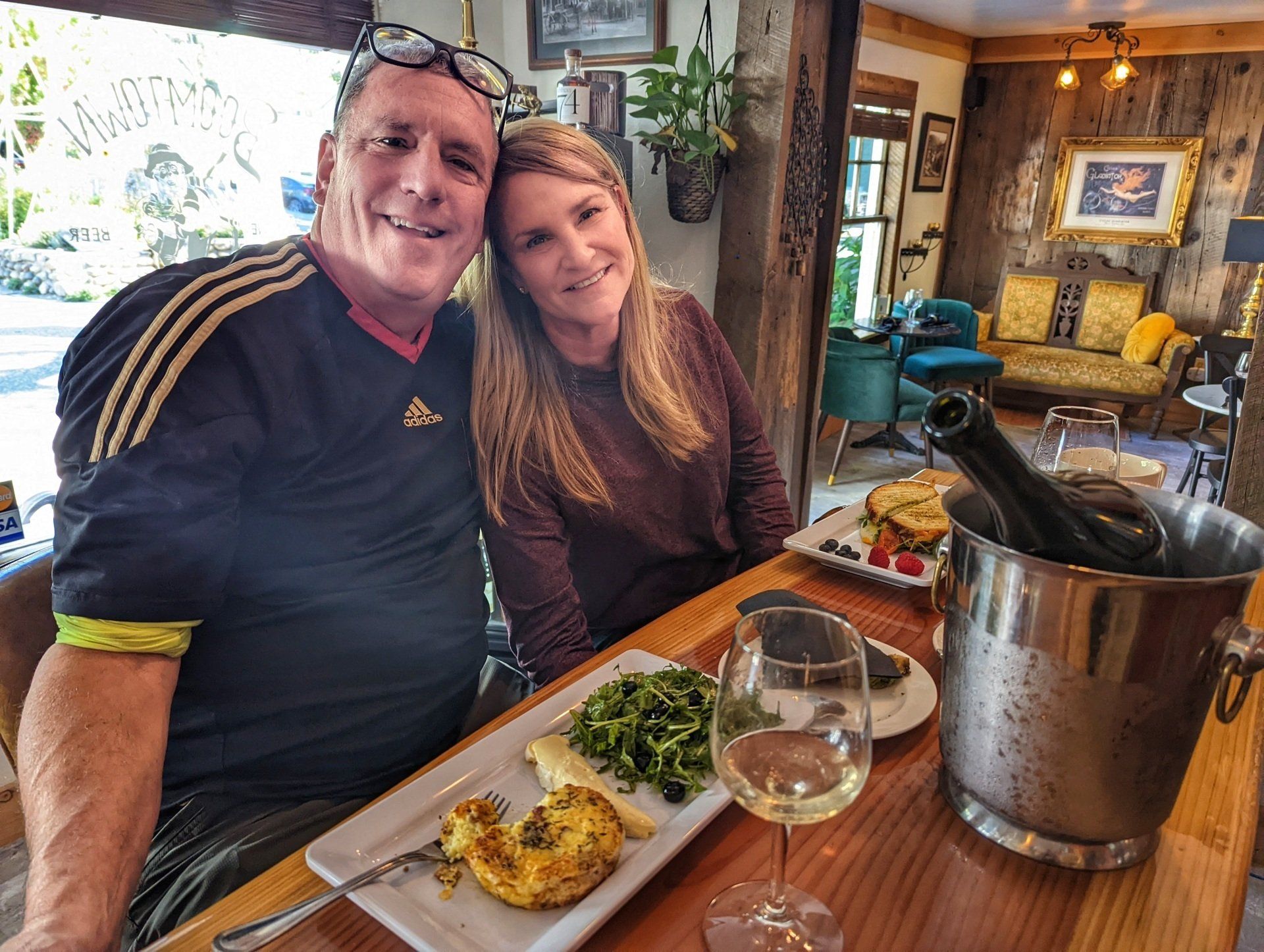 A man and a woman are sitting at a table with plates of food and wine glasses.