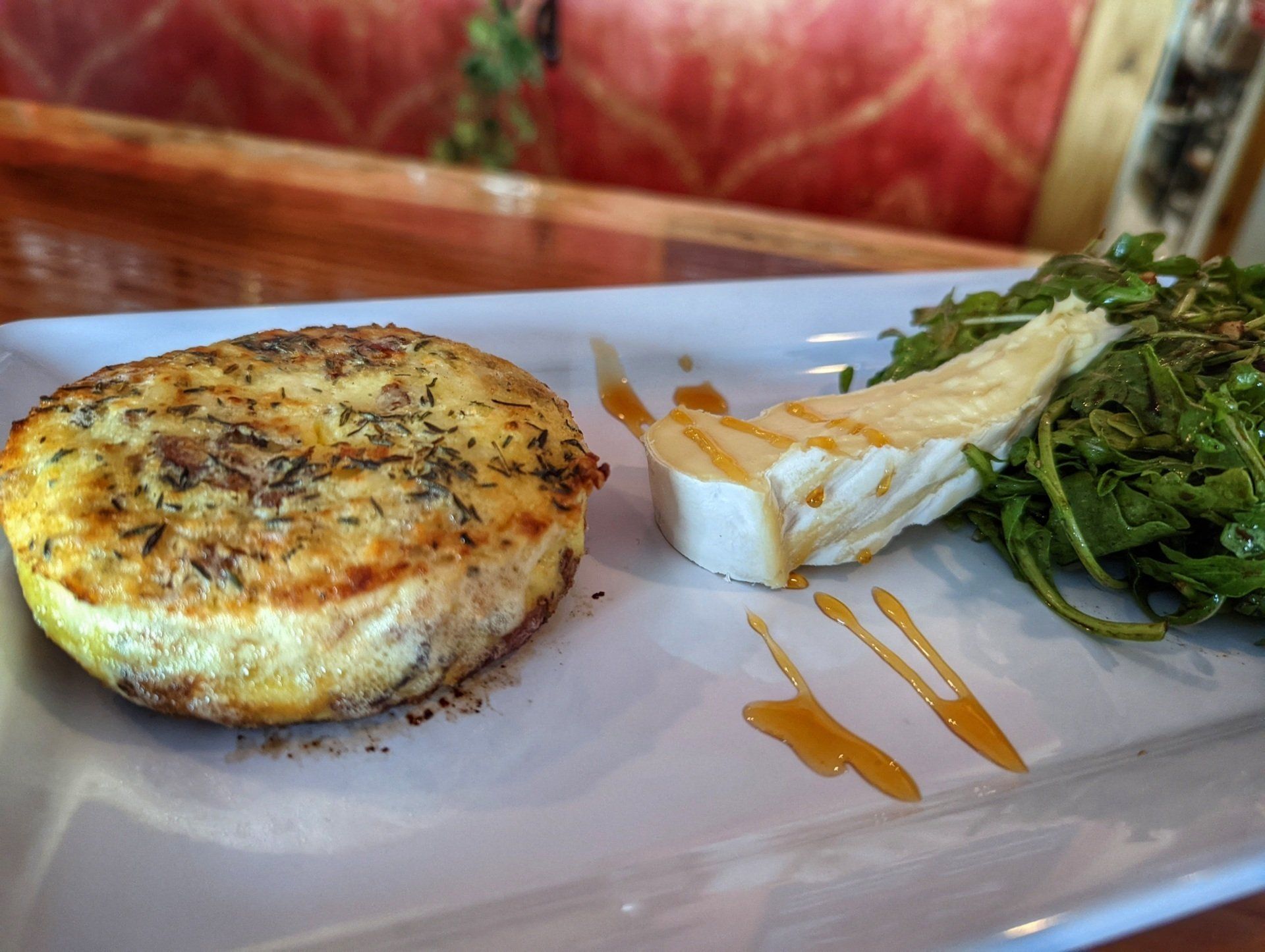 A plate of food with a slice of cheese and a salad on a table.