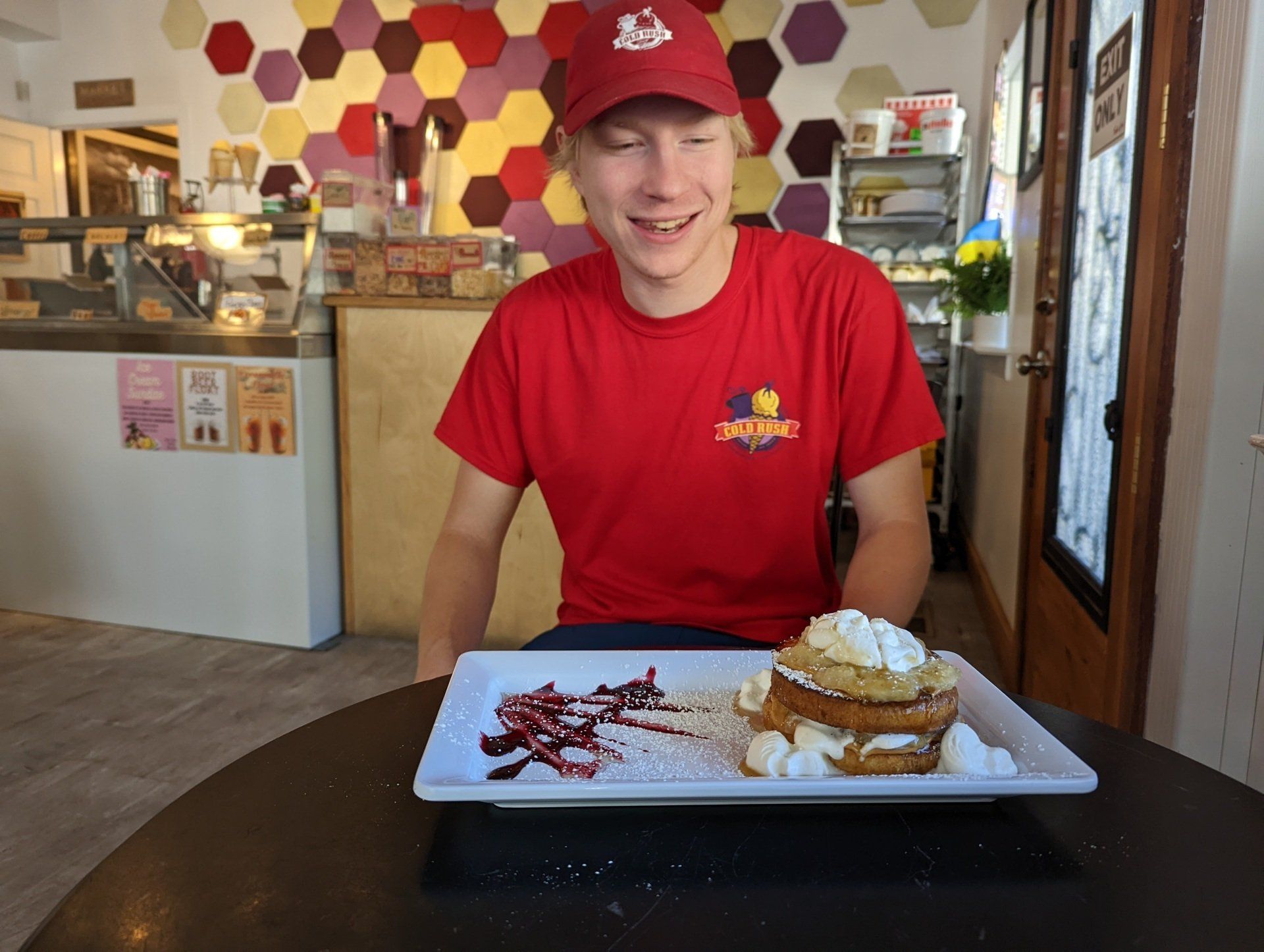 A man in a red shirt is sitting at a table with a plate of food on it