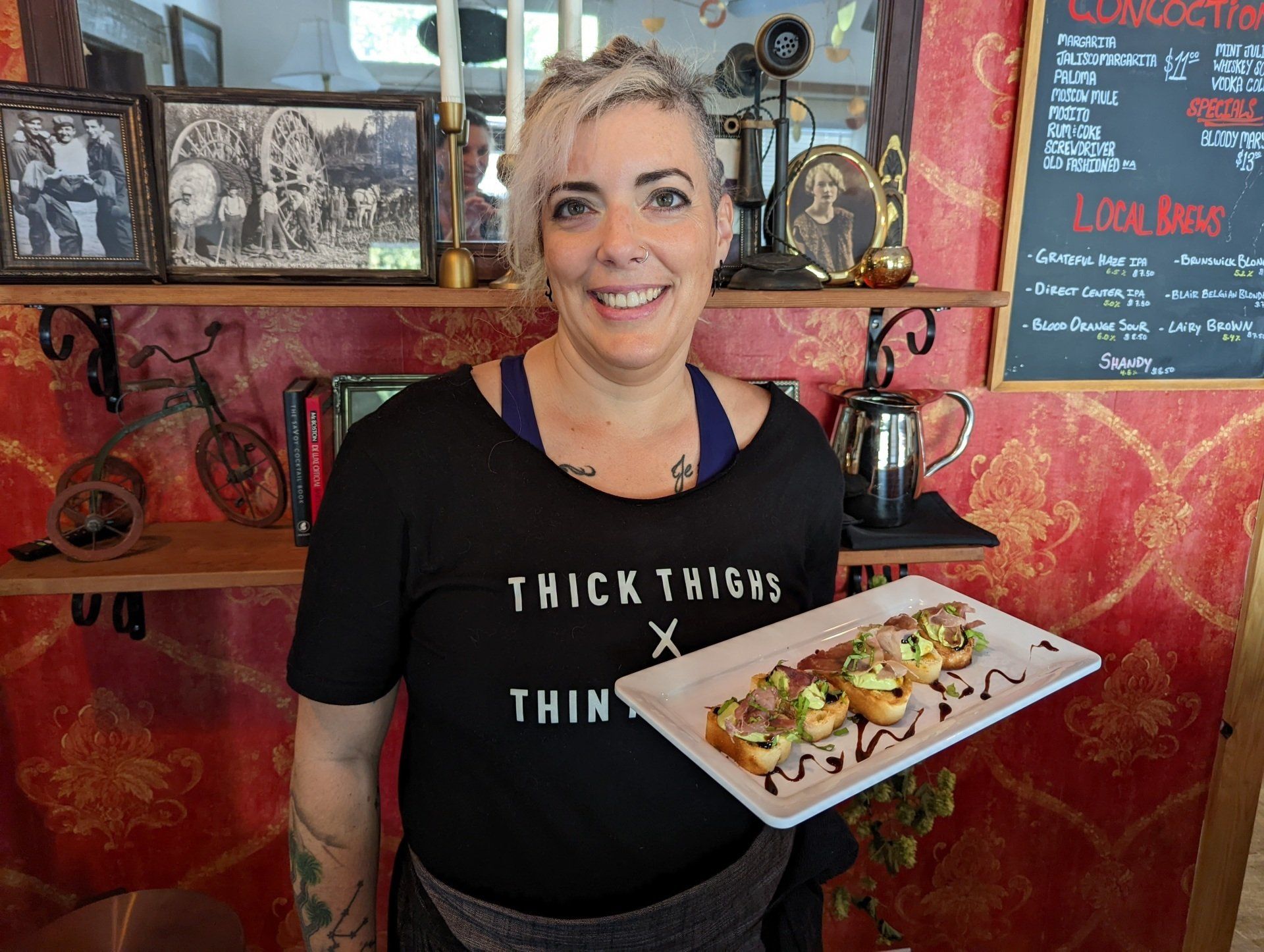 A woman in a thick thighs shirt is holding a plate of food.