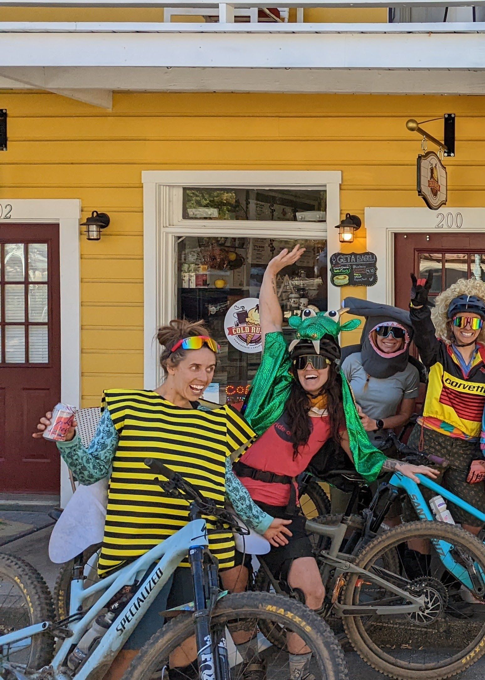 A group of people standing next to bicycles in front of a yellow building.