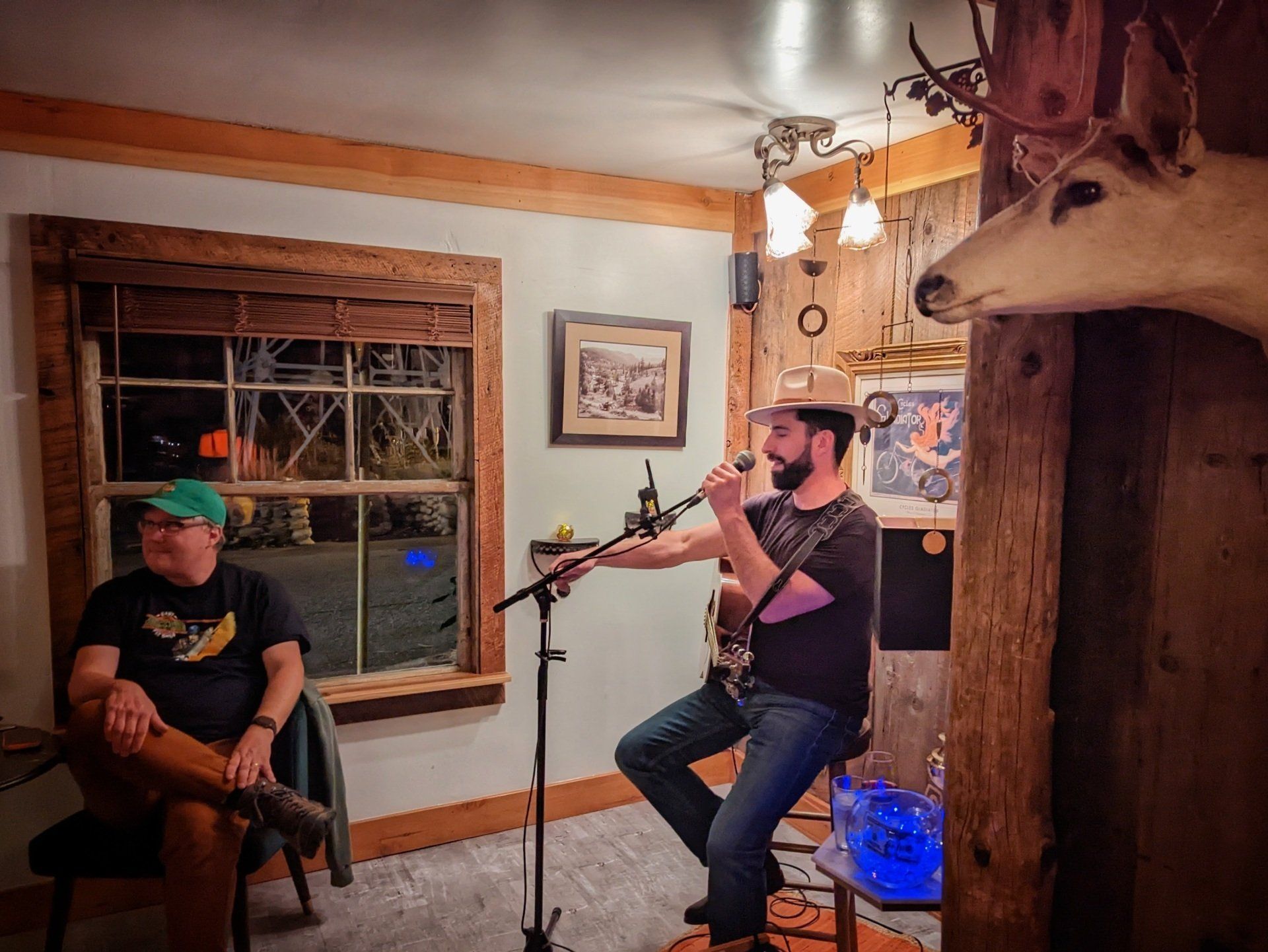 A man is singing into a microphone while another man sits in a chair.
