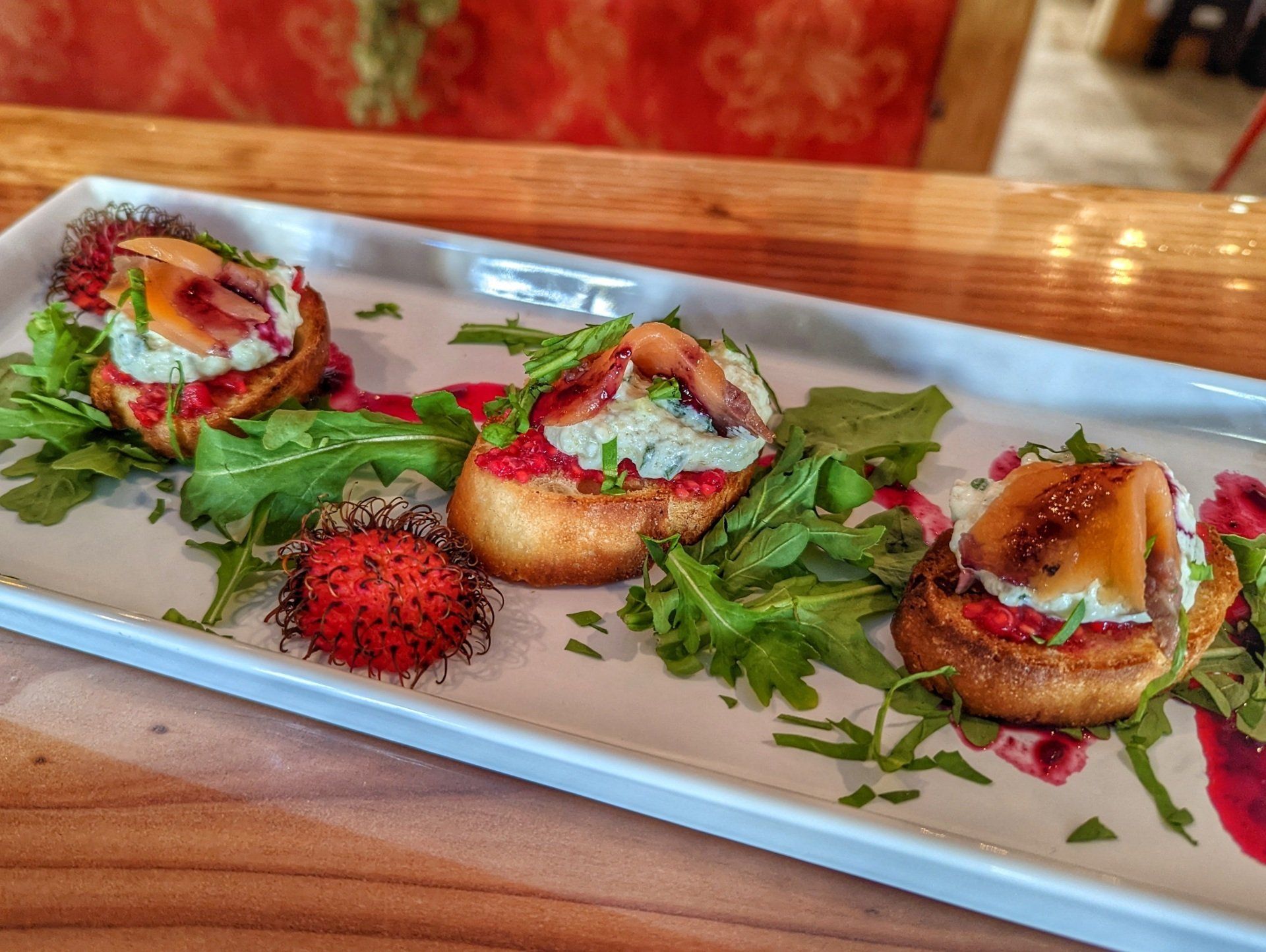 A white plate topped with food and a strawberry on a wooden table.