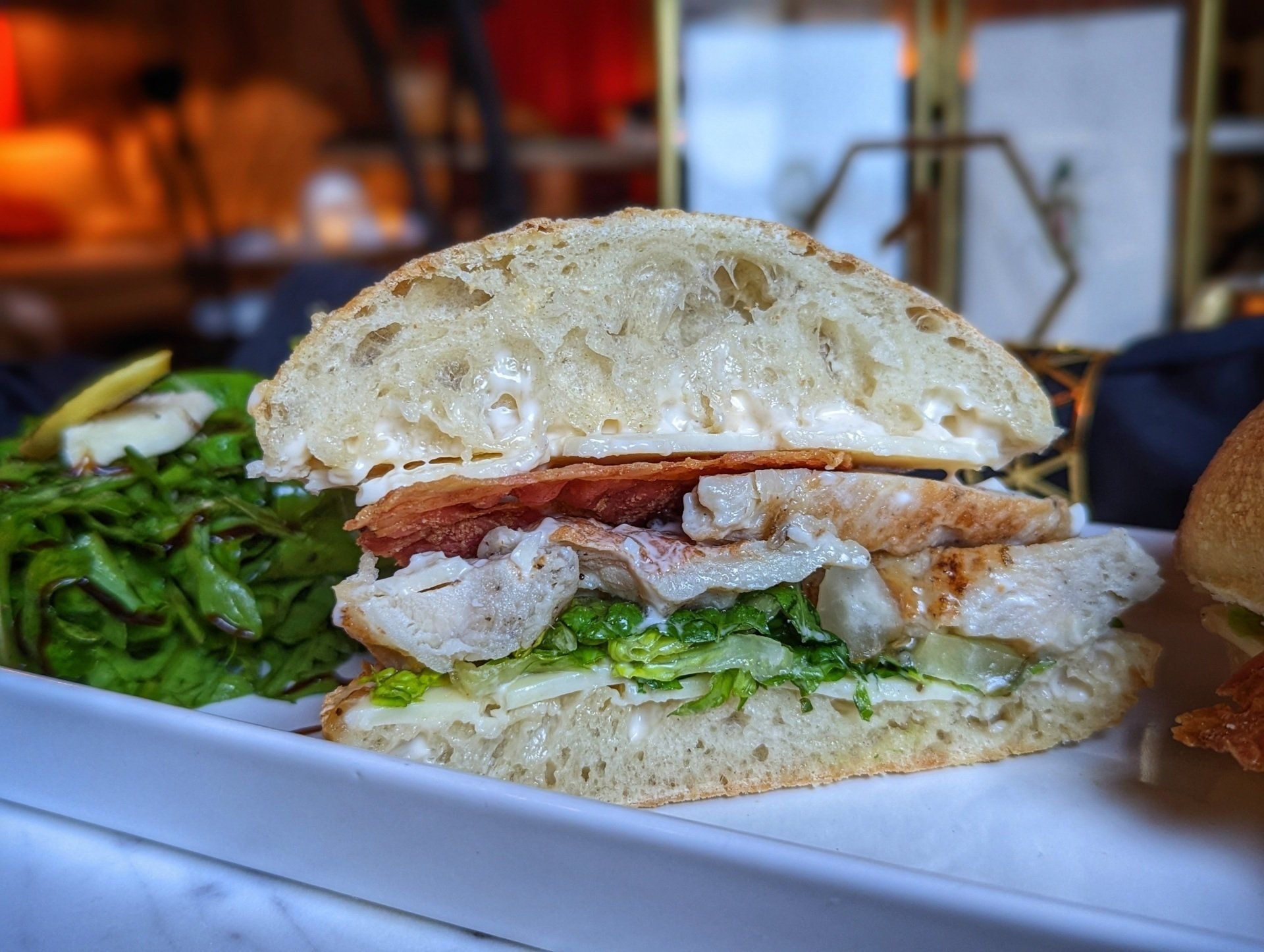 A close up of a sandwich on a plate with a salad.