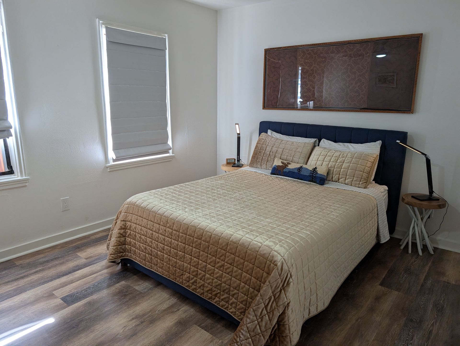 A bedroom with a bed , two windows and a lamp.