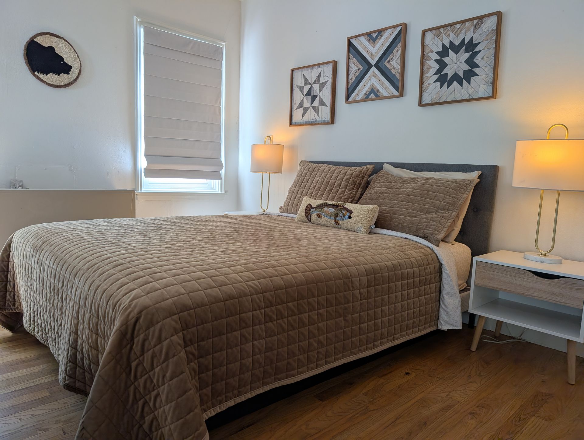 A bedroom with a bed , nightstand , lamps and a window.