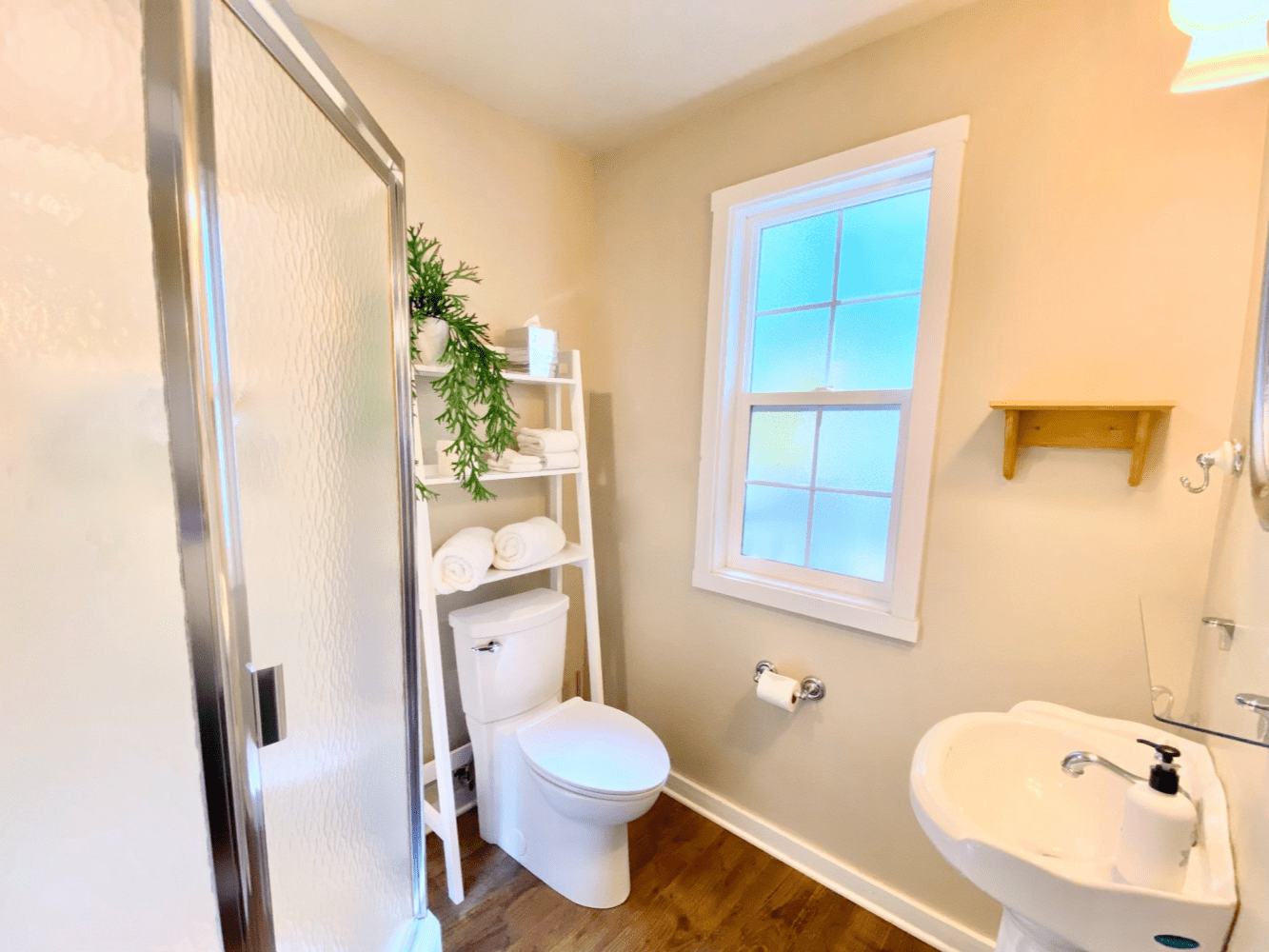 A bathroom with a toilet , sink , shower and window.