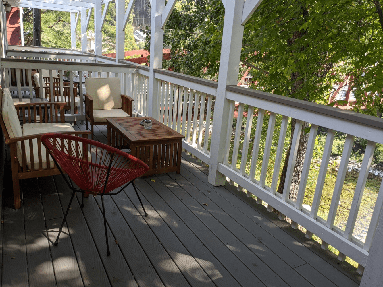 A wooden deck with a red chair and a table