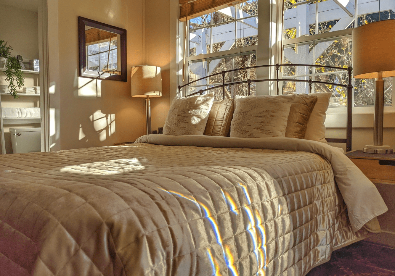 A bedroom with a bed , lamps , a mirror and a window.