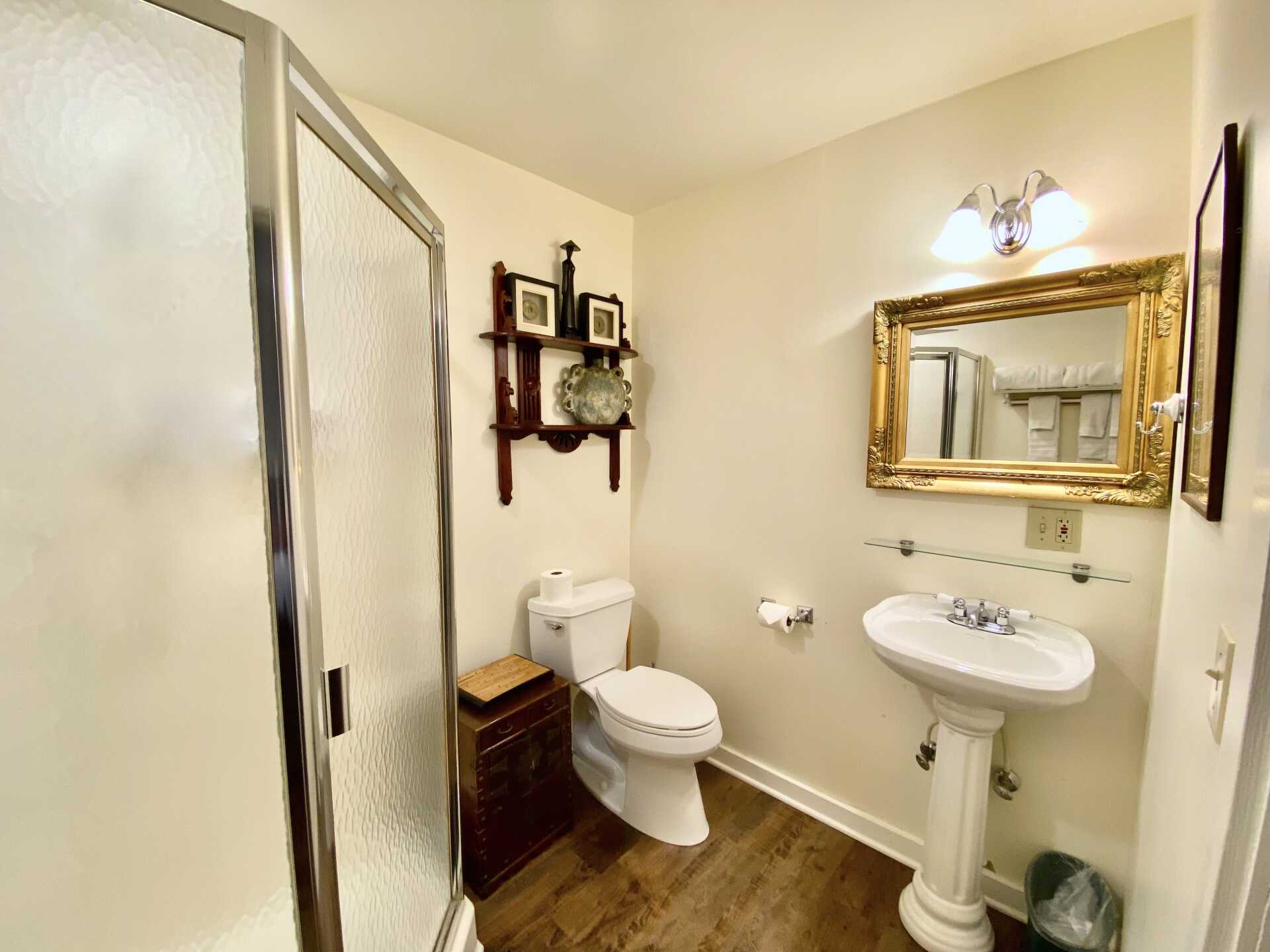 A bathroom with a toilet , sink , shower and mirror.